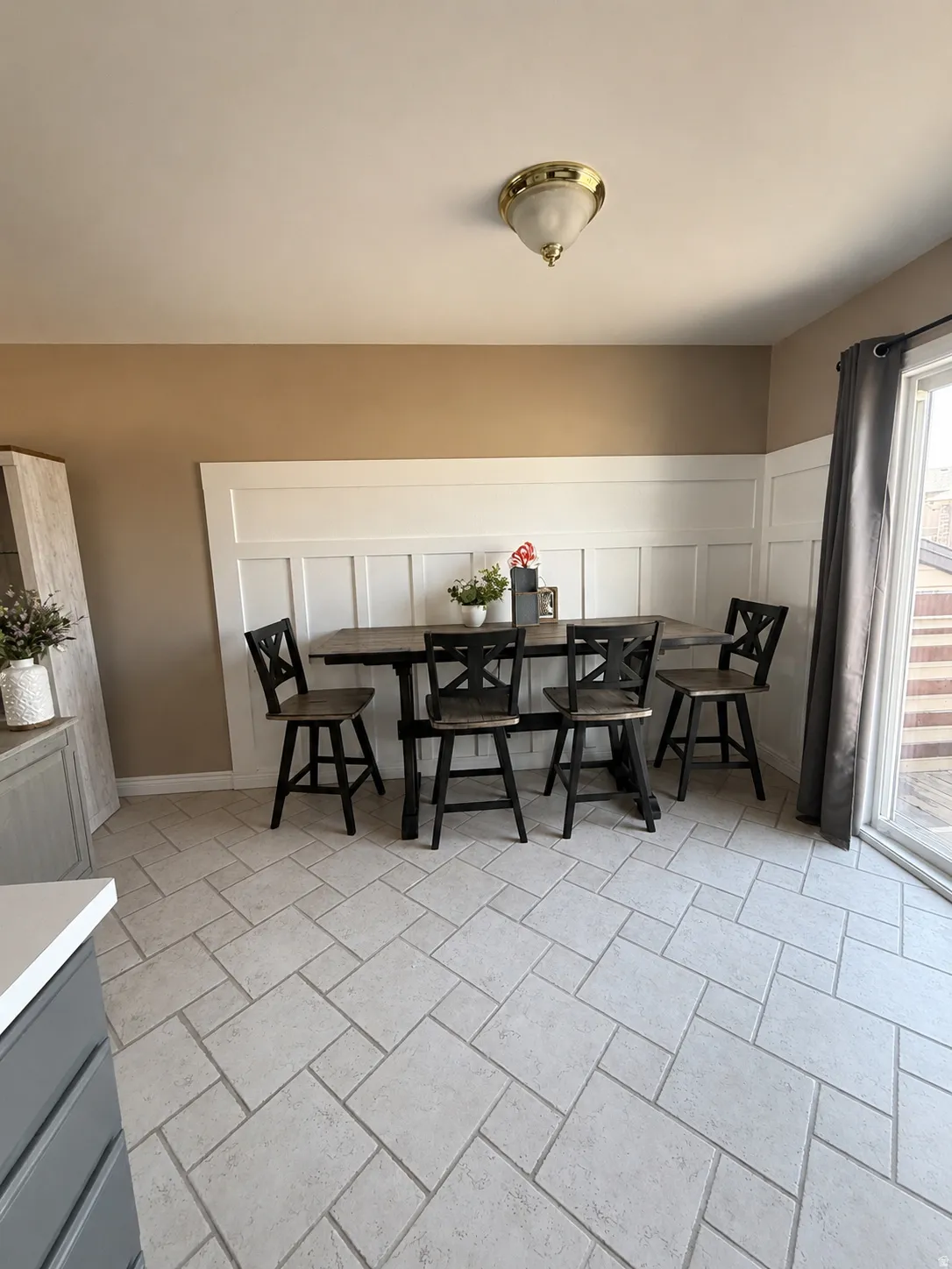 Dining area featuring wainscoting, a flush mount ceiling light fixture, and large format tile flooring