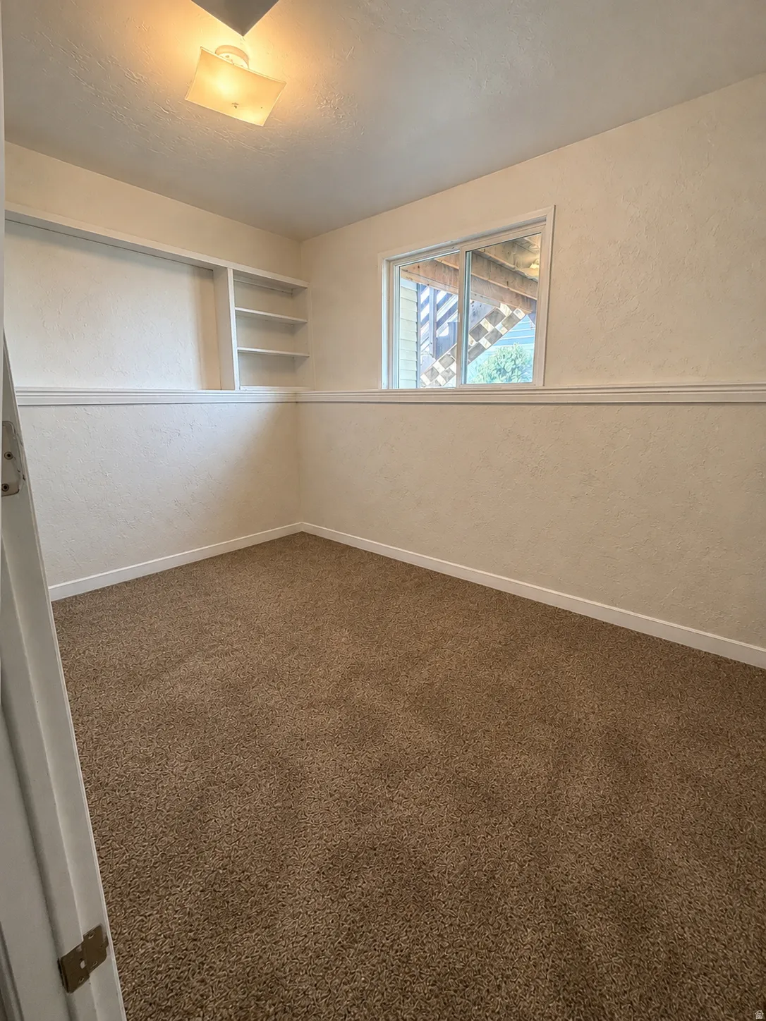 Neutral-toned carpeting paired with white baseboards and chair rail molding