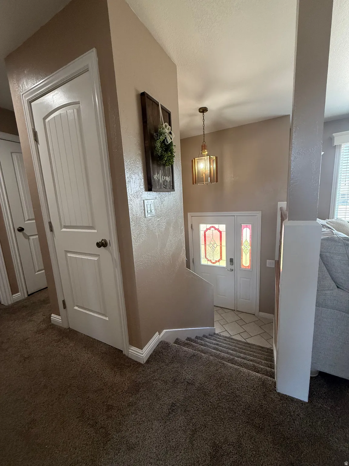 Entryway featuring a decorative pendant light, a double entry door with stained glass panels, and a tiled floor landing