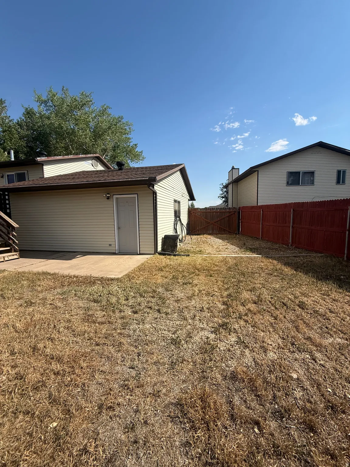 Rear exterior featuring a detached structure with siding and a shingled roof, alongside a concrete patio