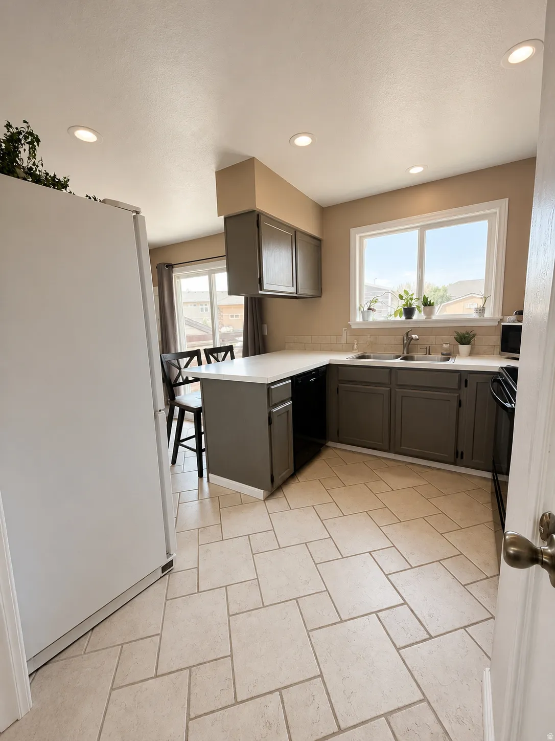 Kitchen featuring light-toned tile flooring, recessed lighting, and a window above the sink