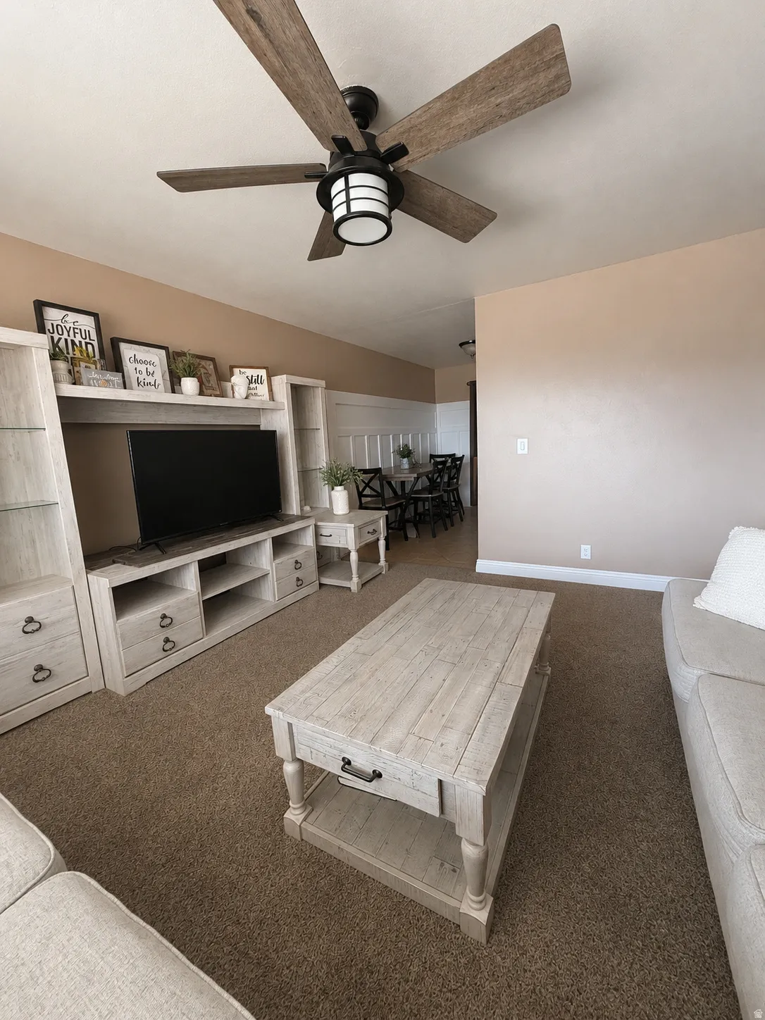 Living area featuring a ceiling fan with wood-finish blades and integrated lighting