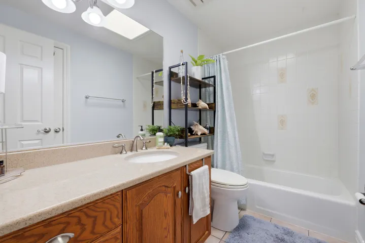 Bathroom featuring a single vanity with a light-toned countertop, an integrated sink, and wood-finish cabinetry