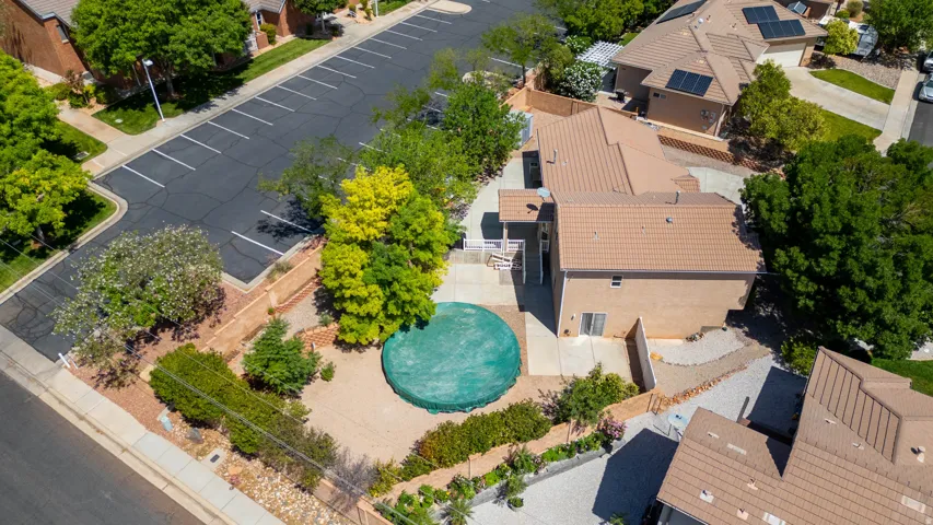 Aerial property view featuring a multi-level structure with a tile roof, an exterior patio, and mature landscaping
