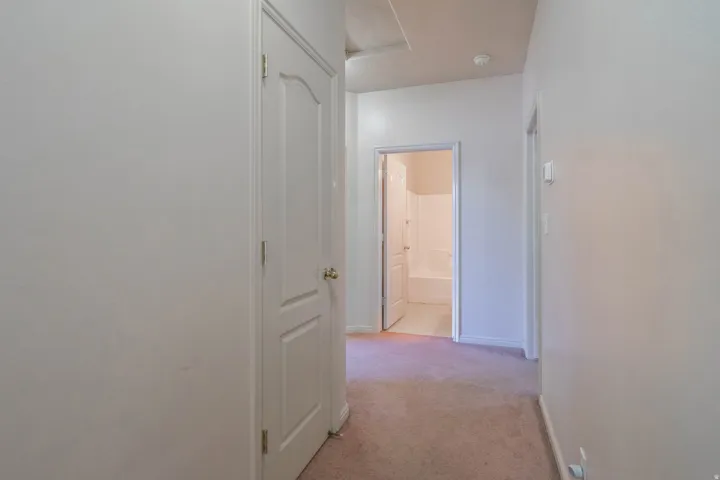 Carpeted hallway featuring white painted walls, white trim, and white doors