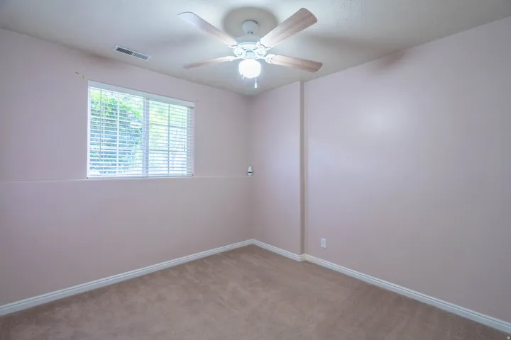 Carpeted room featuring a ceiling fan with light fixture, a window with horizontal blinds, and baseboard molding