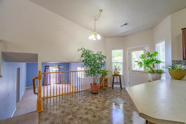 Vaulted ceiling interior featuring a tiled floor, wood railing, and a countertop with built-in cabinetry