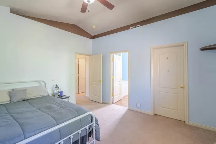 Carpeted interior room with a vaulted ceiling and a ceiling fan