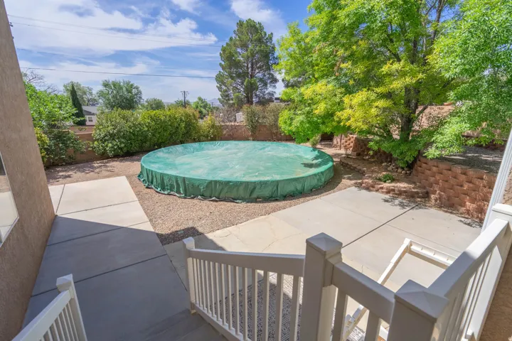 Backyard featuring a covered circular pool, concrete patio, gravel landscaping, and mature trees