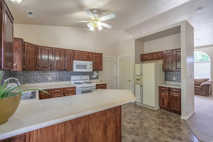 Kitchen featuring wood-finish cabinetry, light-toned countertops, and a mosaic tile backsplash