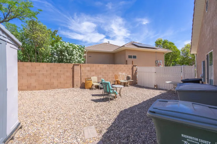 Backyard space featuring gravel landscaping, a block perimeter wall, and a white privacy fence