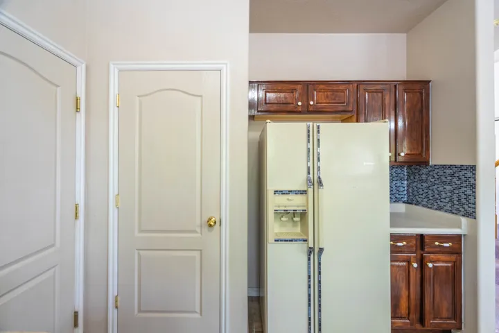 Kitchen area featuring wood cabinetry, light countertops, and a blue mosaic tile backsplash