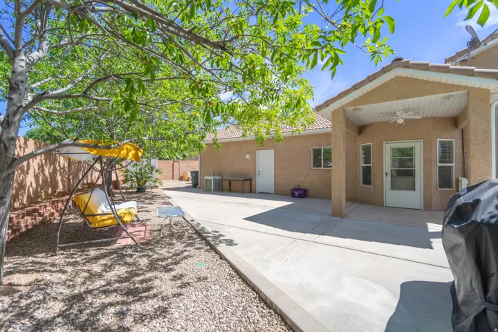 Expansive concrete patio area featuring a covered porch with a ceiling fan