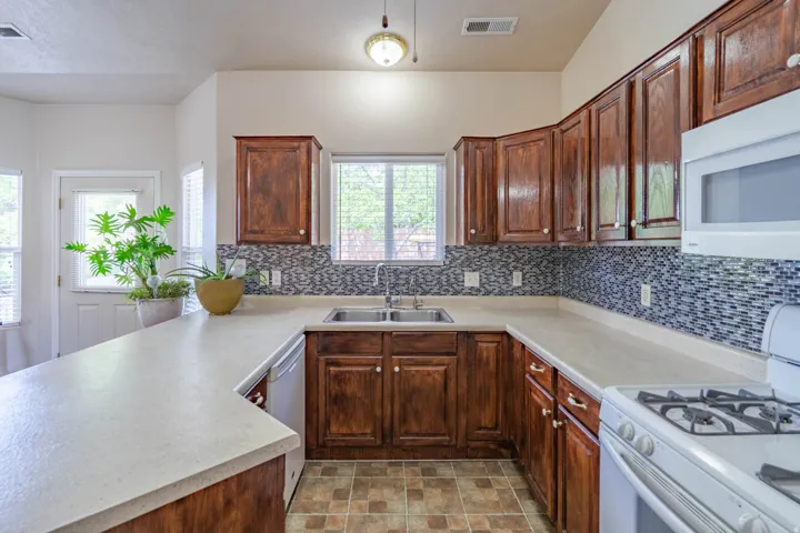 U-shaped kitchen featuring wood cabinetry, light-toned countertops, and a mosaic tile backsplash