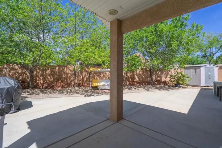 Covered patio with a concrete surface, leading to an expansive yard area