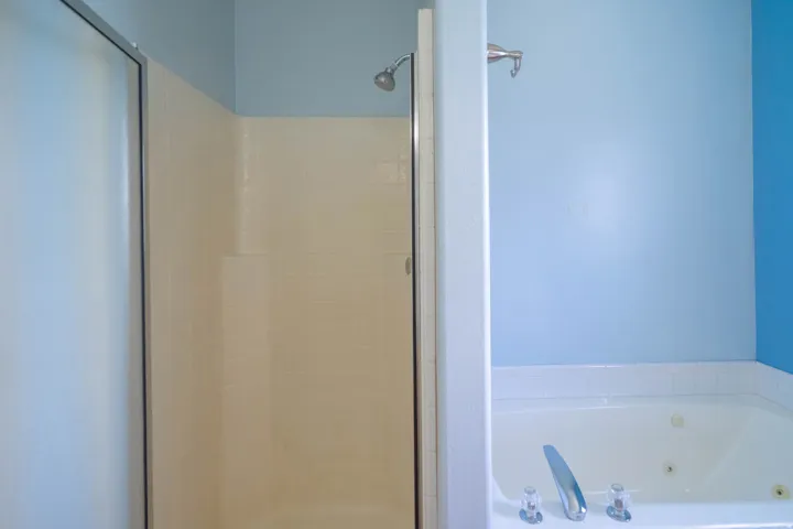 Bathroom featuring a tiled shower enclosure with sliding glass door, a wall-mounted showerhead, and a built-in jetted tub with chrome fixtures