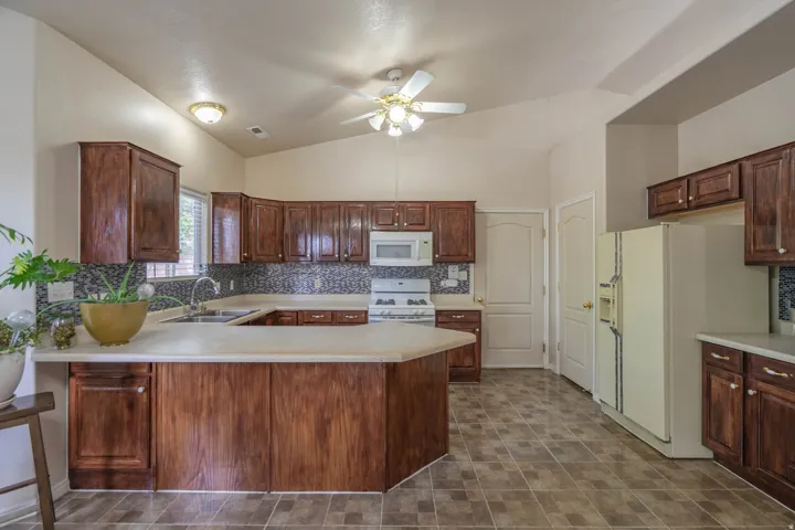 Spacious kitchen featuring a peninsula island, dark wood cabinetry, and a patterned tile backsplash