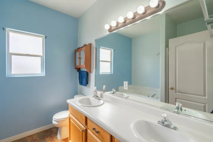 Bathroom featuring a double vanity with light wood cabinetry and white countertops