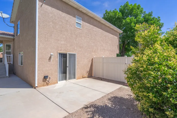 Rear exterior patio featuring concrete surfacing, sliding glass door entry, and an adjacent gravel area