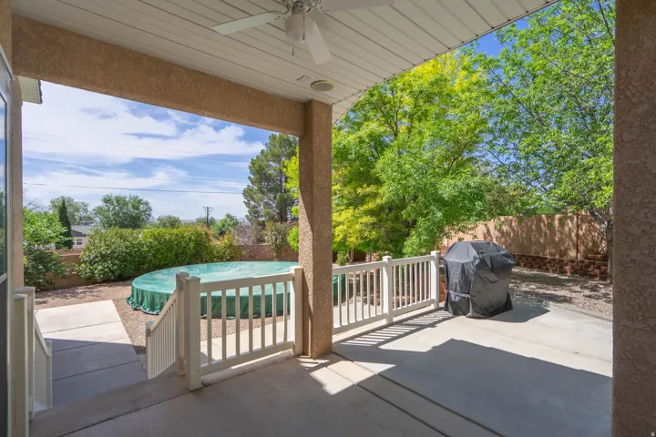 Expansive covered patio featuring a ceiling fan, concrete flooring, and white railing