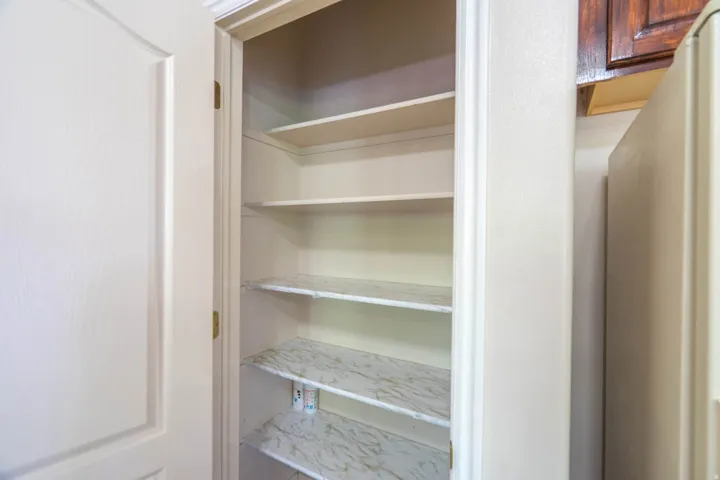 Built-in pantry with multiple white shelves and light-toned shelf liners
