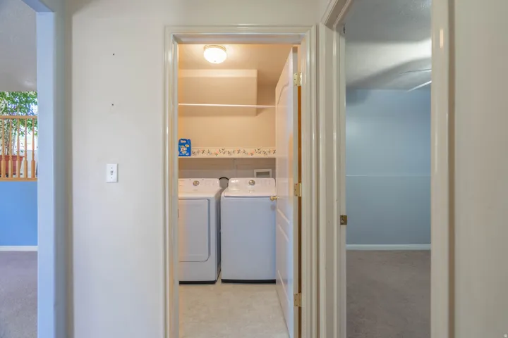 Dedicated laundry closet featuring a built-in shelf, overhead lighting, and resilient flooring