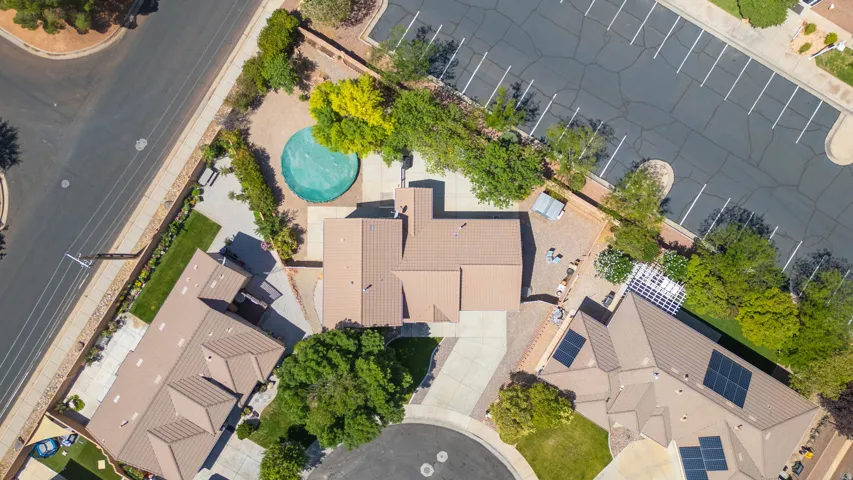 Aerial perspective showcasing a property featuring a covered circular pool, mature landscaping, and a tan tile roof
