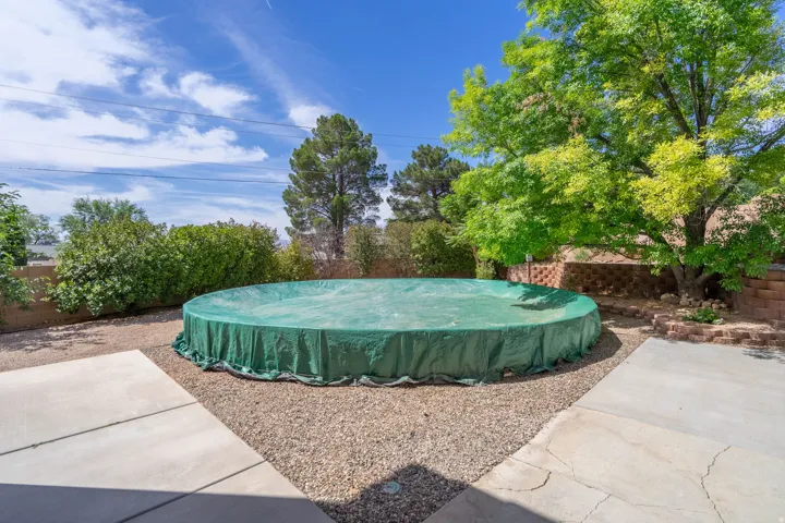 Backyard featuring a round, covered above-ground pool, surrounded by gravel and concrete patio sections
