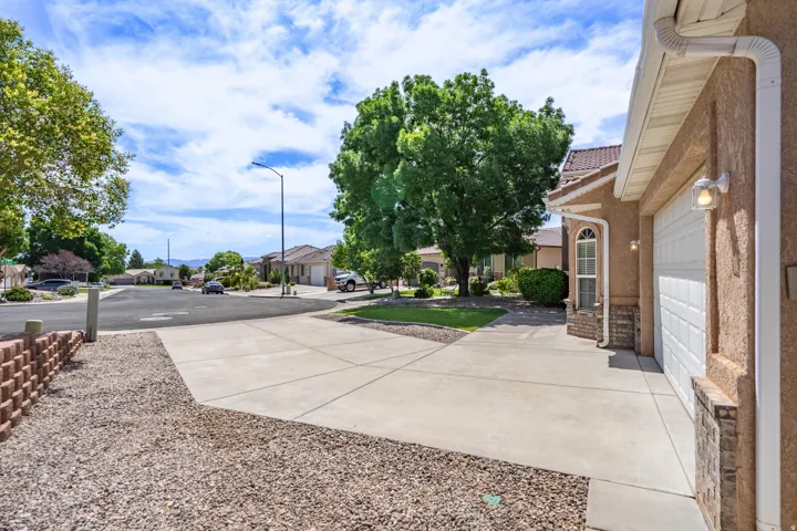 Concrete driveway providing off-street parking, stucco exterior, white garage door, arched window, and stone accenting