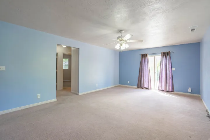 Spacious room with light blue walls and neutral carpeting