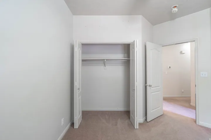 Carpeted room featuring a built-in closet with bi-fold doors and a metal hanging rod