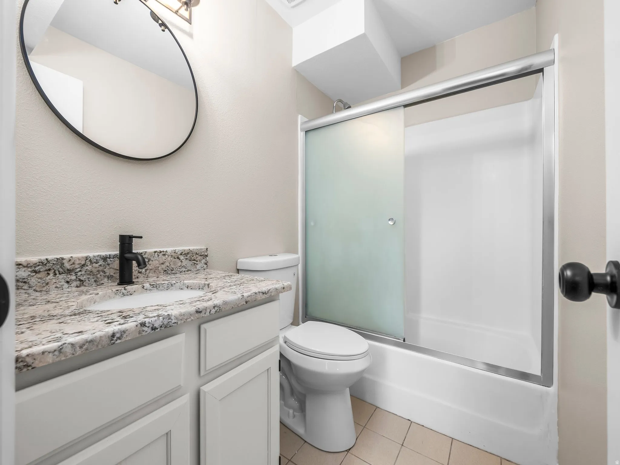 Bathroom featuring a white vanity with a speckled countertop, undermount sink, and matte black faucet