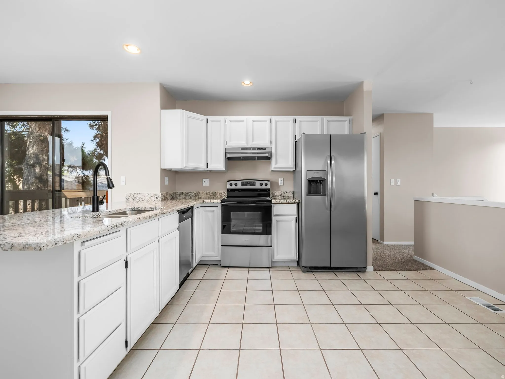 Kitchen featuring white cabinetry, light-toned granite countertops, and stainless steel appliances