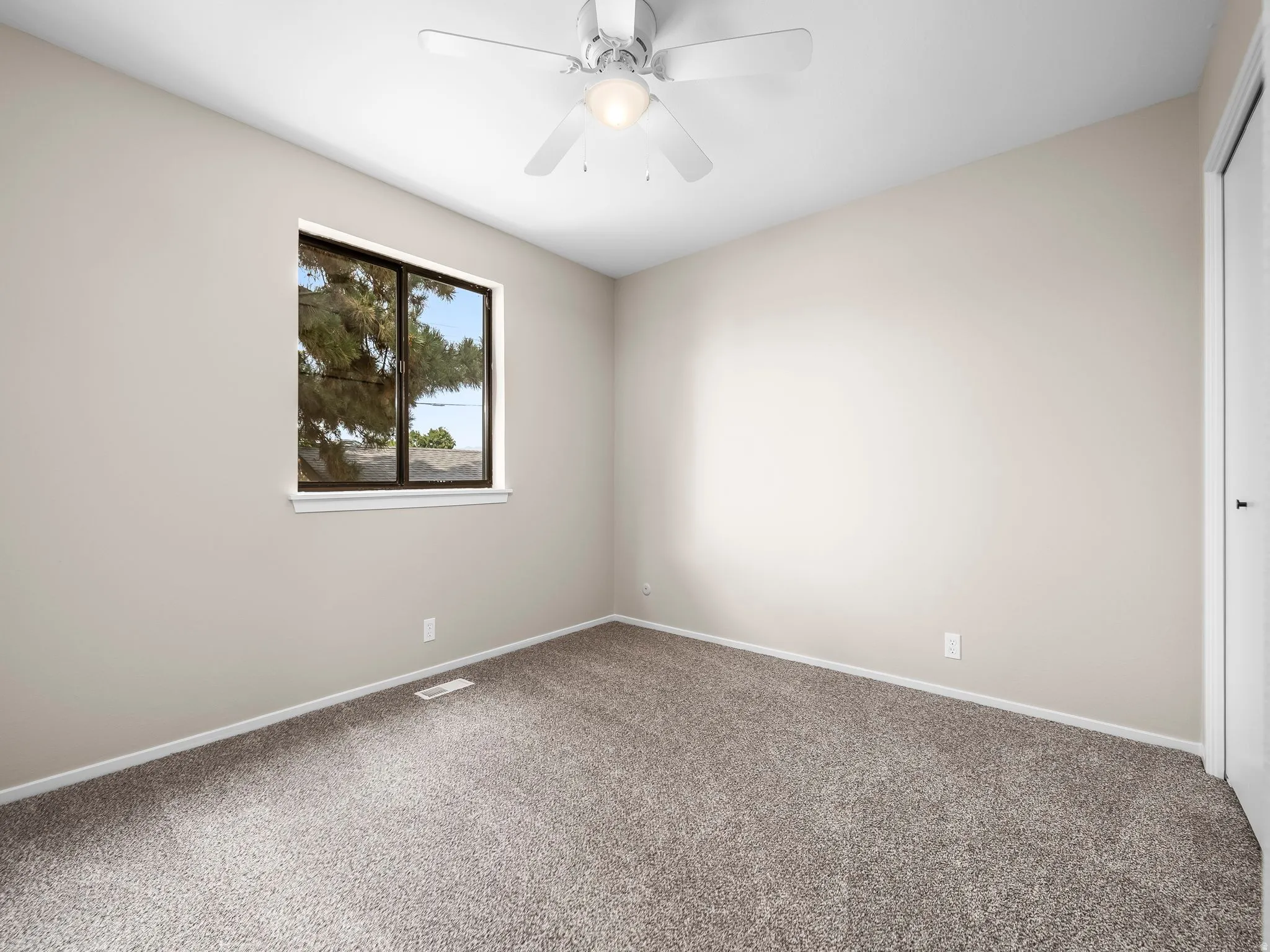 Neutral-toned room featuring a single window with dark framing and a white sill