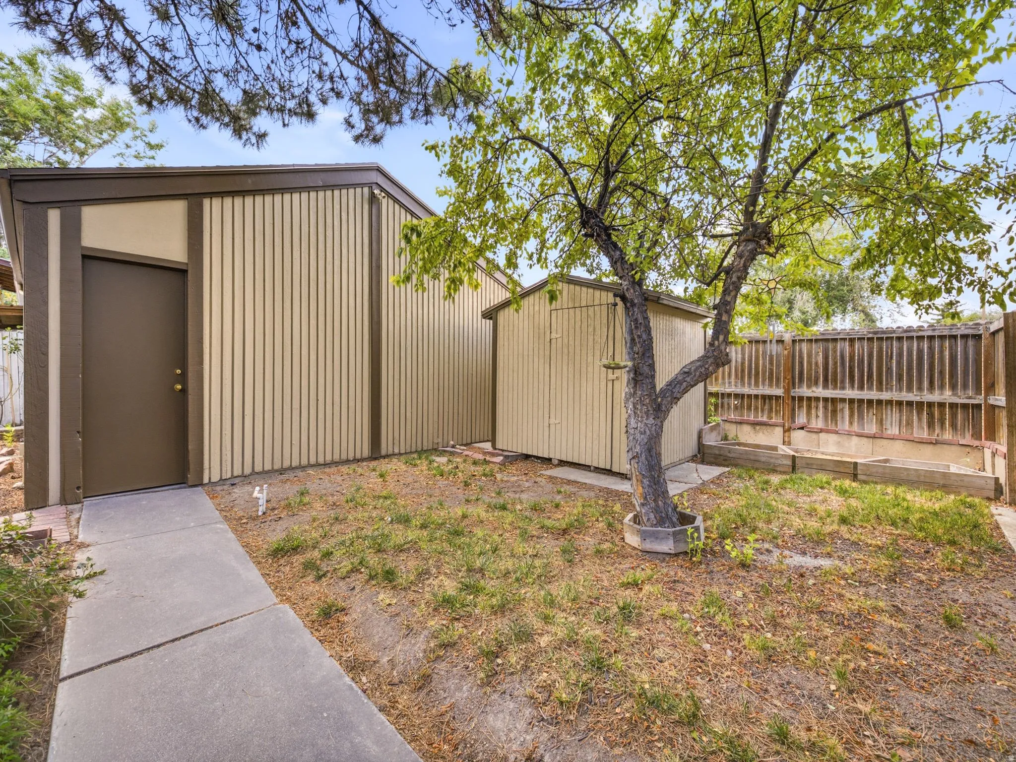 Concrete walkway leading to a brown door within a tan-sided structure