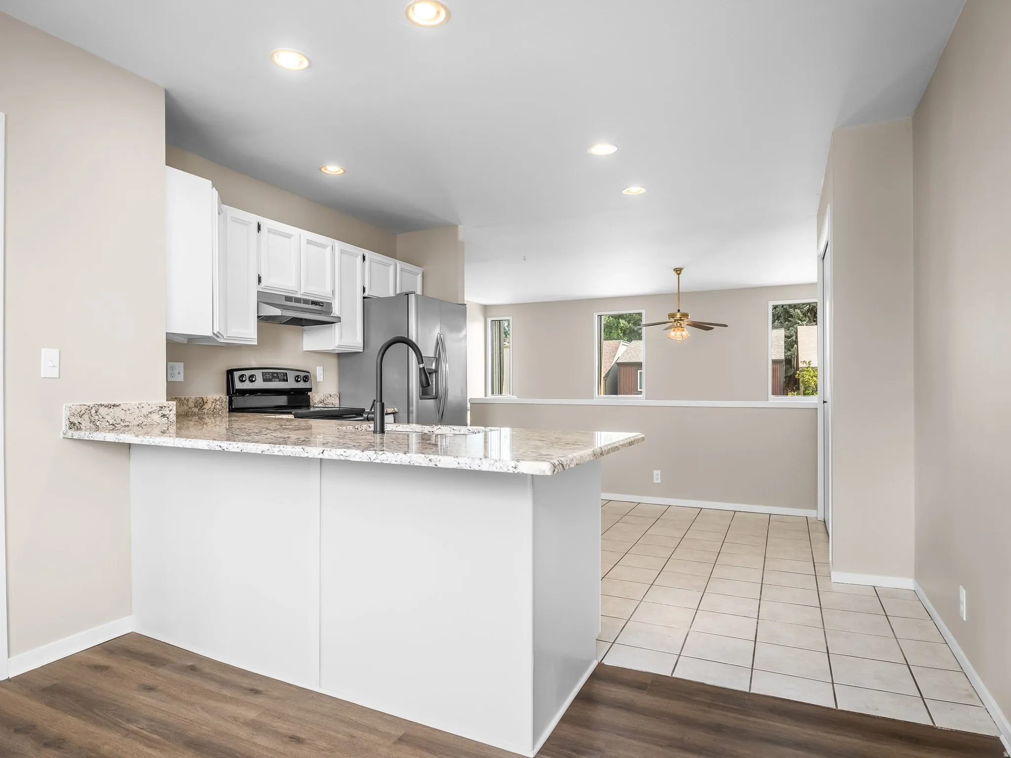 Modern kitchen featuring granite countertops, white cabinetry, and stainless steel appliances