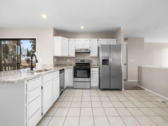 Kitchen featuring white cabinetry, light-toned granite countertops, and stainless steel appliances