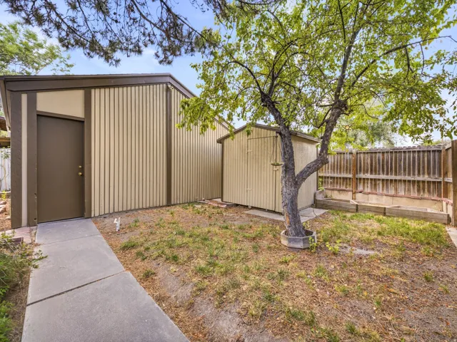 Concrete walkway leading to a brown door within a tan-sided structure
