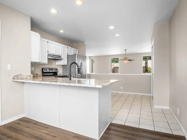 Modern kitchen featuring granite countertops, white cabinetry, and stainless steel appliances