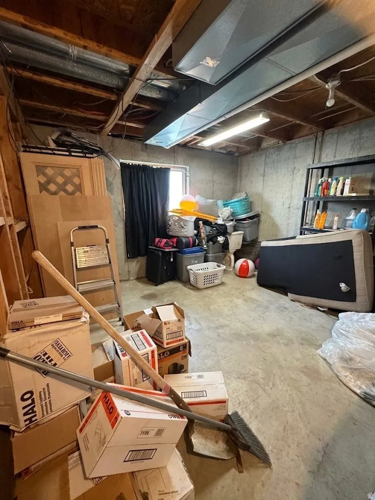 Basement utility space featuring exposed ceiling joists, visible ductwork, and a concrete floor