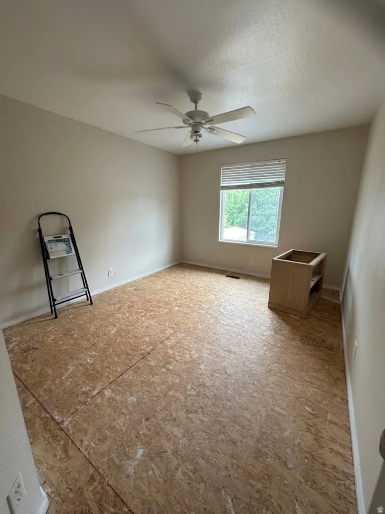 Room featuring a ceiling fan with integrated lighting, a window with horizontal blinds, and subflooring
