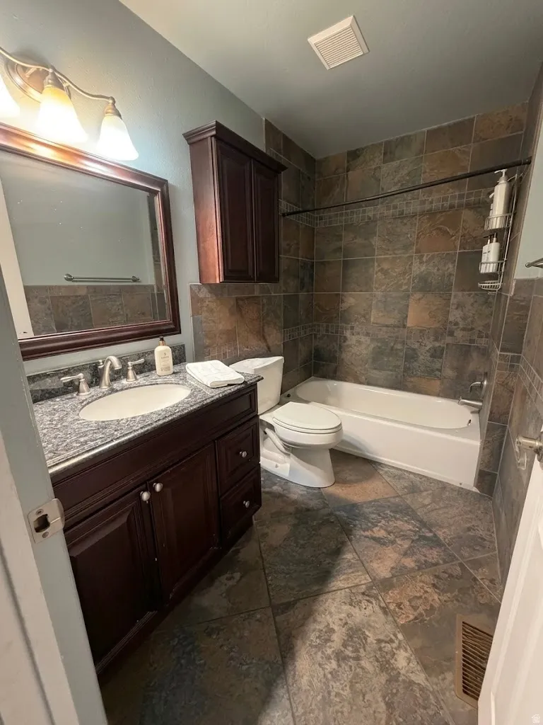Bathroom featuring a dark wood-finish vanity with a granite countertop, undermount sink, and brushed nickel faucet
