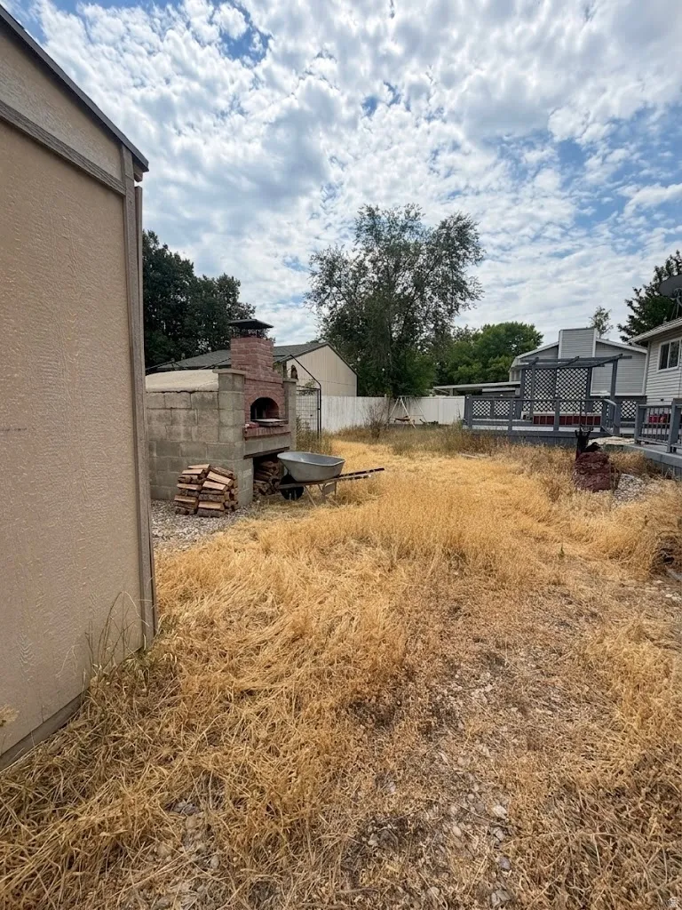 Backyard featuring a brick pizza oven, an adjacent storage shed, and a multi-level deck with a privacy screen