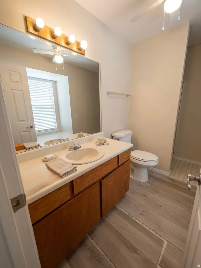 Bathroom featuring a single vanity with built-in cabinetry, ceramic tile flooring, ceiling-mounted fan, and a walk-in shower