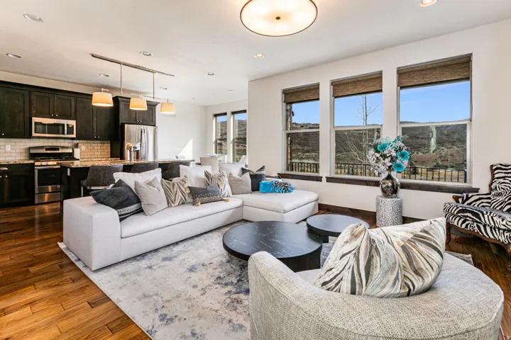 Open-concept living space featuring wood-finish flooring, a kitchen with dark cabinetry and stainless steel appliances, a tiled backsplash, and recessed lighting