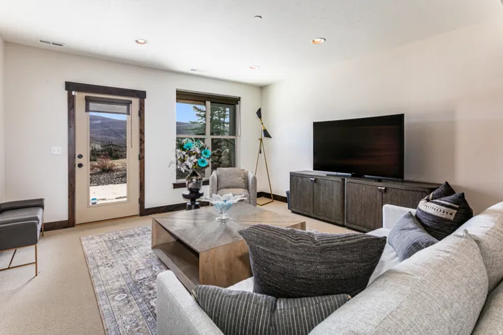 Spacious living area featuring light-toned carpeting and recessed lighting