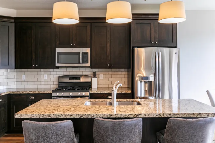 Kitchen featuring dark wood cabinetry, light granite countertops, and stainless steel appliances