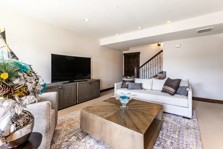 Living area featuring a textured wood-finish coffee table, recessed lighting, and a dark wood door