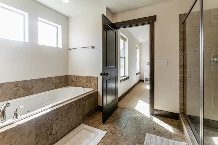 Soaking tub with brushed nickel fixtures, surrounded by large format tile