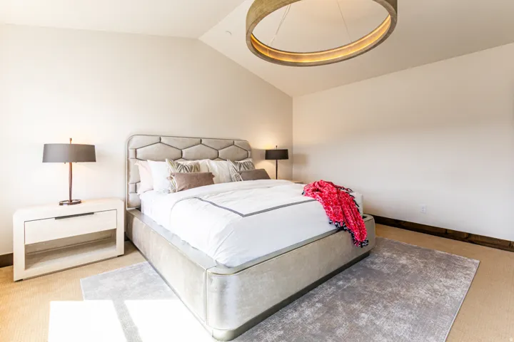 Spacious room featuring vaulted ceilings, a contemporary ceiling light fixture, light-toned carpeting, and dark wood-finish baseboards